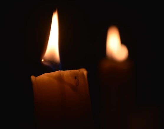 Two lit candles in darkness symbolizing remembrance for cremation services in Prosper, TX.