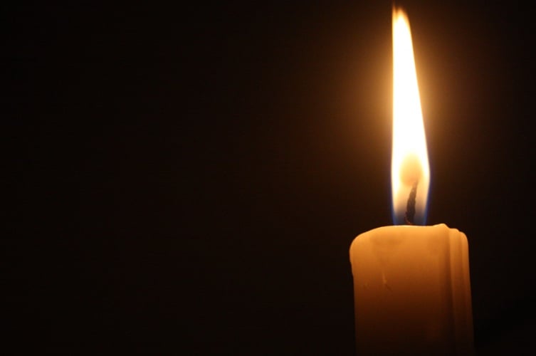 Single candle flame glowing softly during a memorial moment in Frisco, TX.