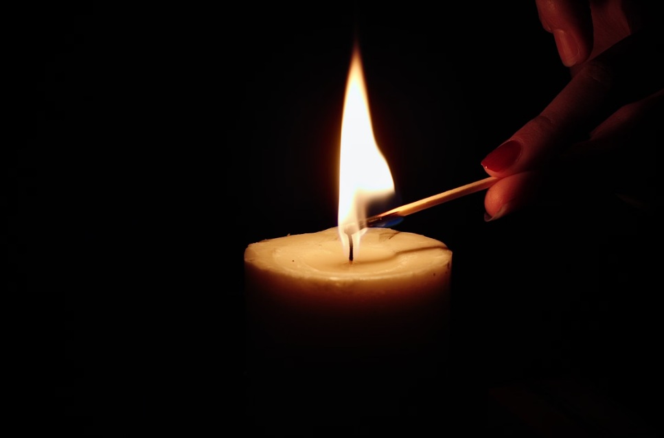 Hand lighting a memorial candle for lasting remembrance in Prosper, TX.